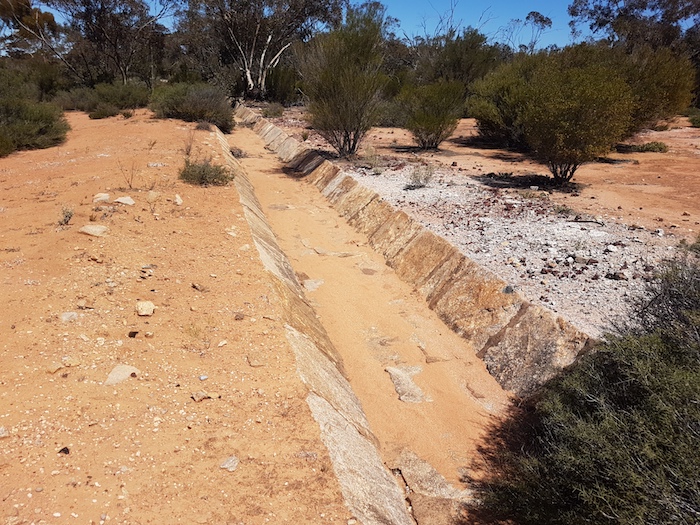 Water harvesting channel directs water from the rock into the dam.